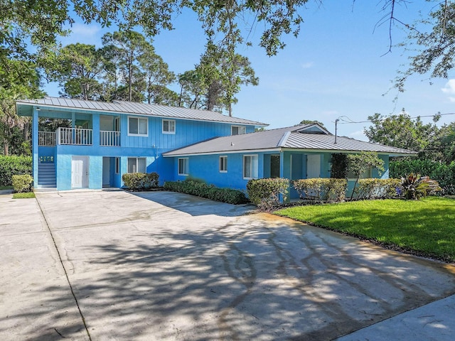 6881 Church St, Jupiter, FL 33458 - view of front of home featuring metal roof, concrete driveway, a standing seam roof, a front lawn, and stucco siding