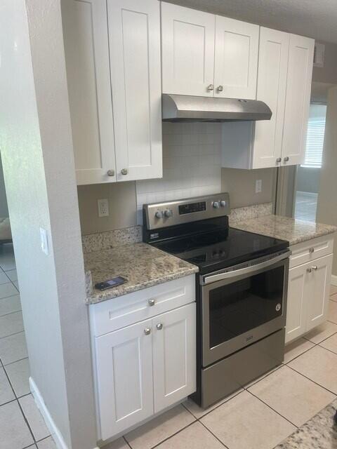 6881 Church St, Jupiter, FL 33458 - kitchen featuring white cabinets, stainless steel electric stove, under cabinet range hood, and light stone counters