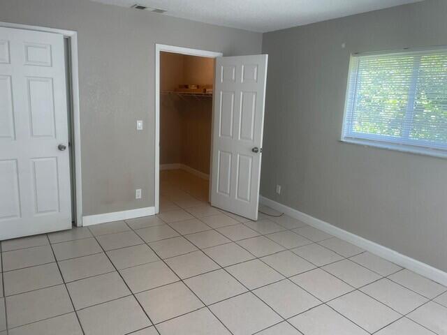 6881 Church St, Jupiter, FL 33458 - unfurnished bedroom featuring light tile patterned floors, a walk in closet, baseboards, and visible vents