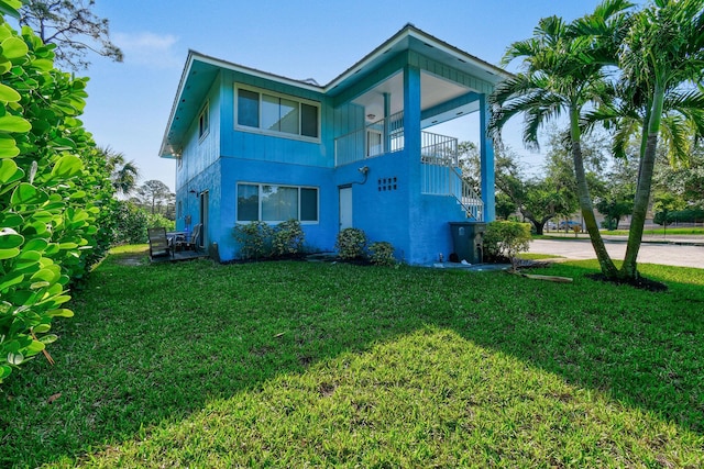 6881 Church St, Jupiter, FL 33458 - rear view of property with a balcony, stucco siding, and a lawn