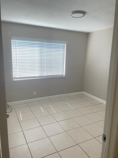 6881 Church St, Jupiter, FL 33458 - empty room featuring light tile patterned flooring, baseboards, and a textured ceiling