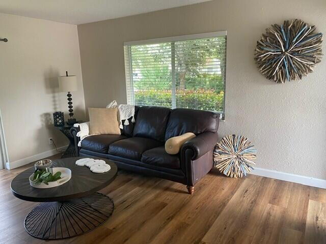 6881 Church St, Jupiter, FL 33458 - living room featuring a textured wall, baseboards, and wood finished floors