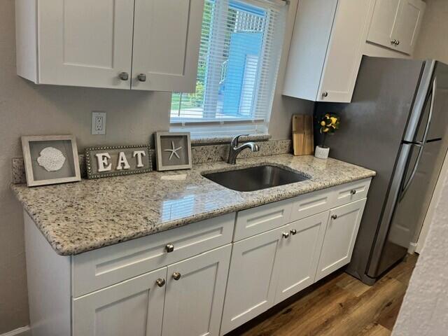 6881 Church St, Jupiter, FL 33458 - kitchen featuring light stone counters, a sink, freestanding refrigerator, white cabinetry, and dark wood-style floors