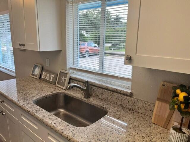 6881 Church St, Jupiter, FL 33458 - kitchen featuring white cabinetry, a sink, and light stone counters