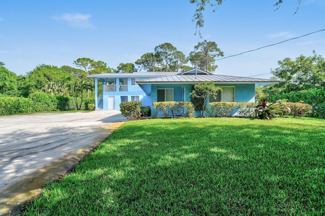 6881 Church St, Jupiter, FL 33458 - view of front of house featuring driveway, metal roof, a front yard, a standing seam roof, and stucco siding