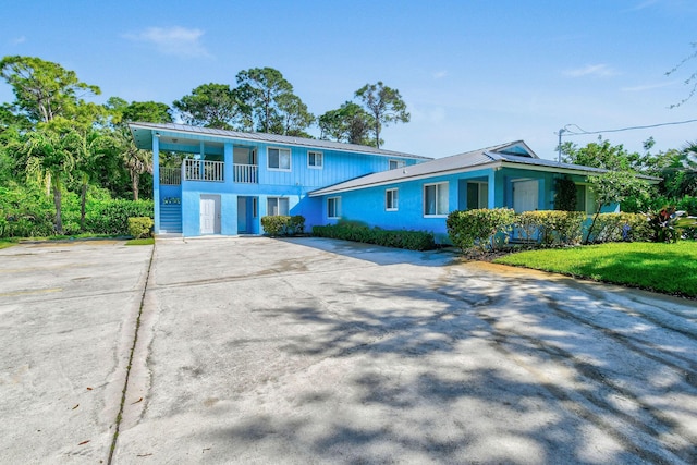 6881 Church St, Jupiter, FL 33458 - view of front of house featuring a front yard, a balcony, and concrete driveway