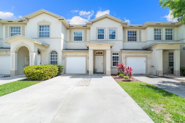 view of property with a garage, driveway, and stucco siding