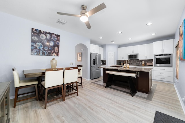 kitchen featuring tasteful backsplash, arched walkways, white cabinetry, visible vents, and appliances with stainless steel finishes
