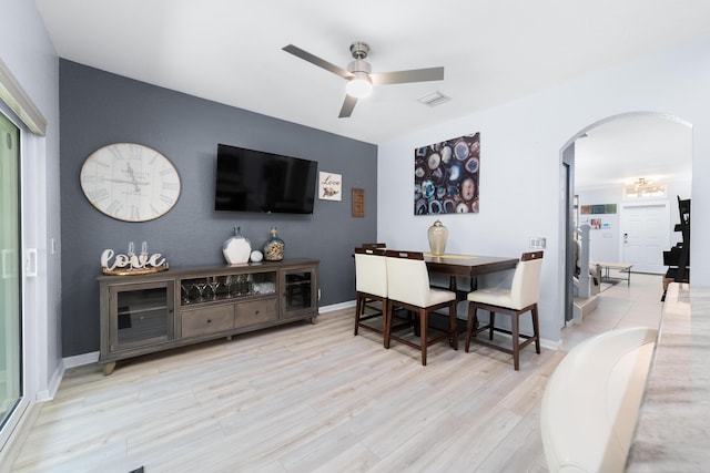 dining area featuring baseboards, visible vents, ceiling fan, arched walkways, and wood finished floors