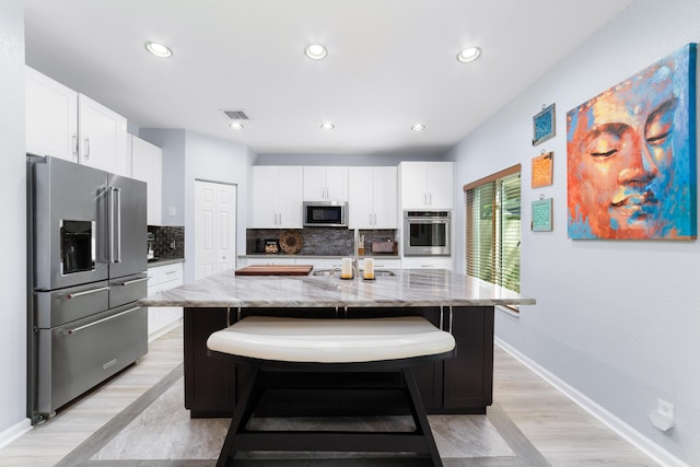kitchen featuring light stone countertops, tasteful backsplash, white cabinets, visible vents, and appliances with stainless steel finishes