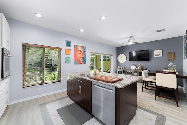 kitchen featuring an island with sink, dark brown cabinets, visible vents, appliances with stainless steel finishes, and a sink