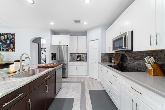 kitchen featuring white cabinets, visible vents, appliances with stainless steel finishes, arched walkways, and a sink