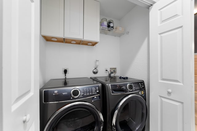 clothes washing area featuring separate washer and dryer and cabinet space