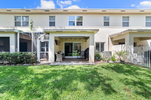 rear view of property featuring a yard, a patio area, stucco siding, and fence