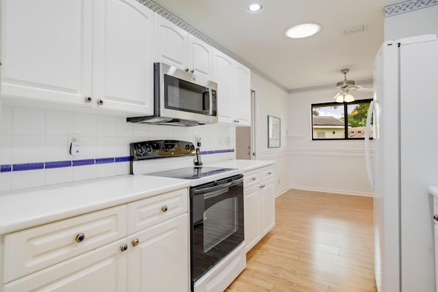 kitchen with light wood-style floors, electric range oven, freestanding refrigerator, stainless steel microwave, and tasteful backsplash