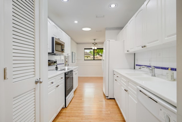 kitchen with a sink, white cabinetry, decorative backsplash, and white appliances