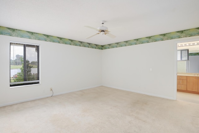 unfurnished room featuring baseboards, light carpet, and ceiling fan