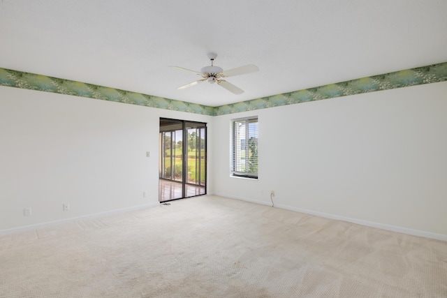 spare room featuring baseboards, light colored carpet, and ceiling fan