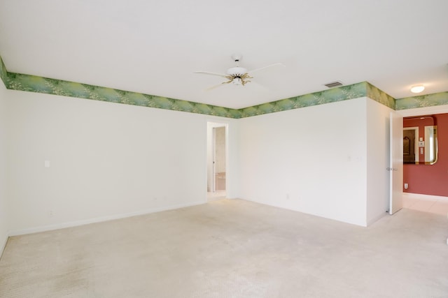 empty room featuring light colored carpet, ceiling fan, visible vents, and baseboards