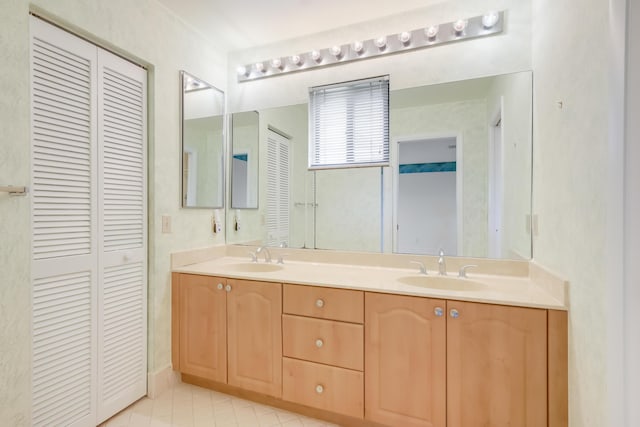 bathroom with a closet, a sink, tile patterned floors, and double vanity