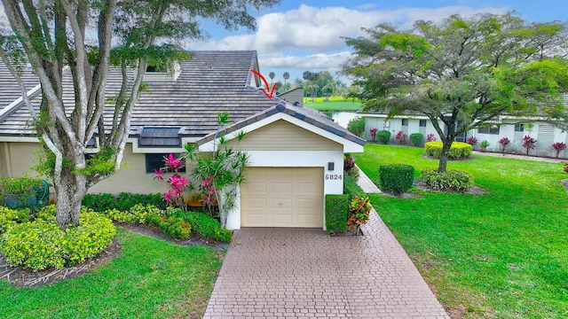 view of front of house featuring stucco siding, decorative driveway, a front yard, and a garage