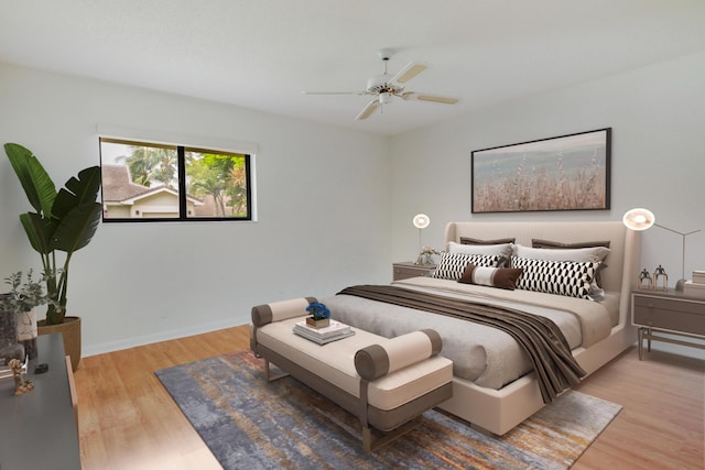 bedroom with light wood-style floors, a ceiling fan, and baseboards