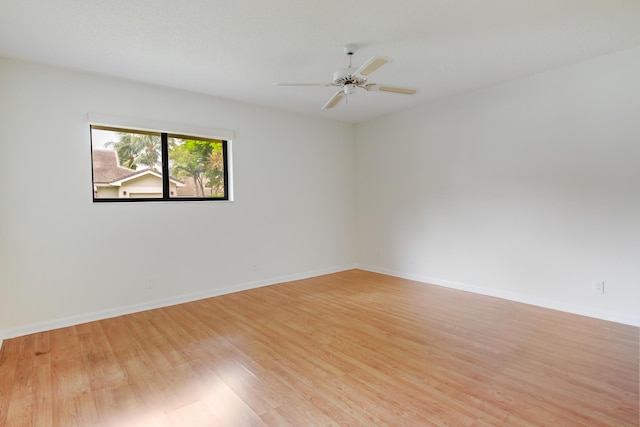 empty room featuring ceiling fan, baseboards, and light wood finished floors