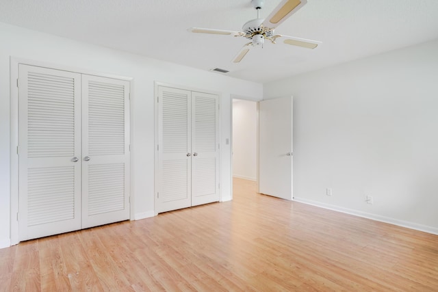 unfurnished bedroom with ceiling fan, multiple closets, light wood-style flooring, baseboards, and visible vents