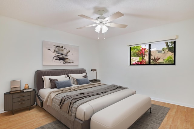 bedroom featuring baseboards, a ceiling fan, and light wood finished floors