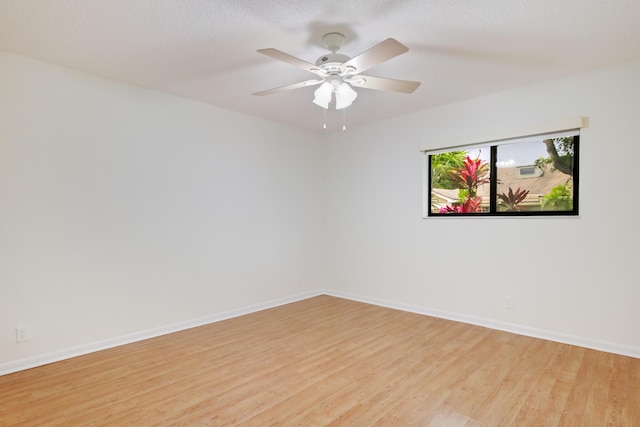 spare room with baseboards, ceiling fan, and light wood-style floors