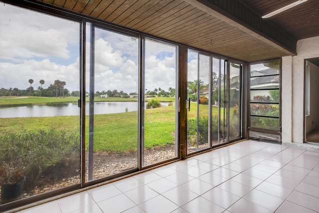unfurnished sunroom featuring a wall of windows, a water view, and tile patterned floors