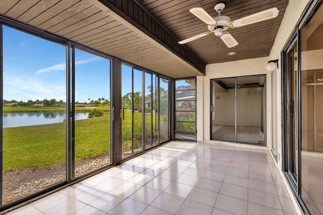 unfurnished sunroom featuring a ceiling fan and a water view