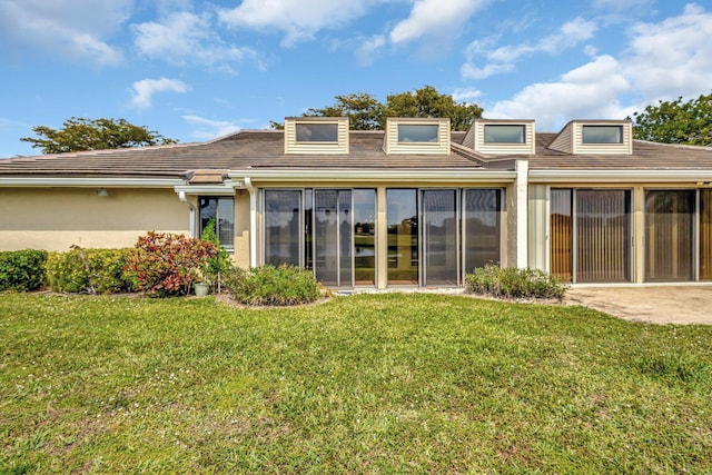 back of property featuring a yard, stucco siding, and a sunroom