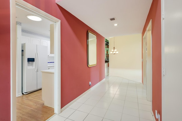 corridor featuring an inviting chandelier, baseboards, and visible vents