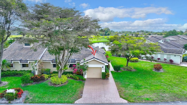 view of front facade with a front lawn, a garage, stucco siding, a water view, and driveway