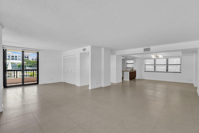 277 N Ocean Blvd Unit 1010, Boca Raton, FL 33432 - unfurnished living room featuring a textured ceiling, a chandelier, and baseboards