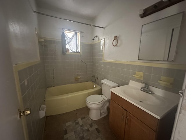 bathroom with a wainscoted wall, toilet, vanity, tub / shower combination, and tile walls
