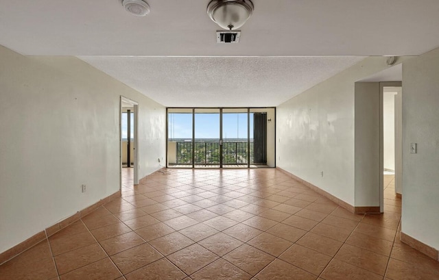 spare room with expansive windows, tile patterned floors, baseboards, and a textured ceiling