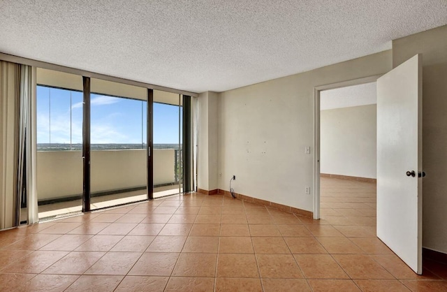 unfurnished room with a textured ceiling, light tile patterned floors, expansive windows, and baseboards