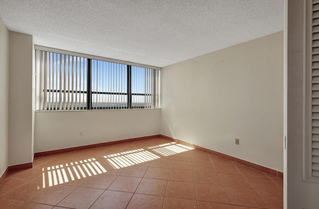 tiled spare room with a textured ceiling, baseboards, and built in shelves