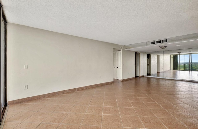 unfurnished room featuring a textured ceiling, baseboards, and light tile patterned floors