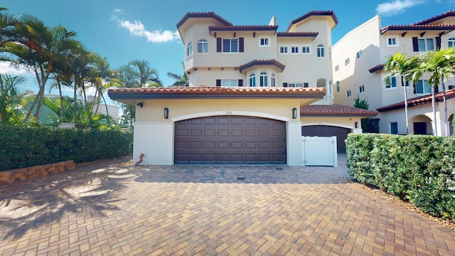 1942 NE 6th St, Deerfield Beach, FL 33441 - mediterranean / spanish-style home featuring stucco siding, a tile roof, an attached garage, and driveway