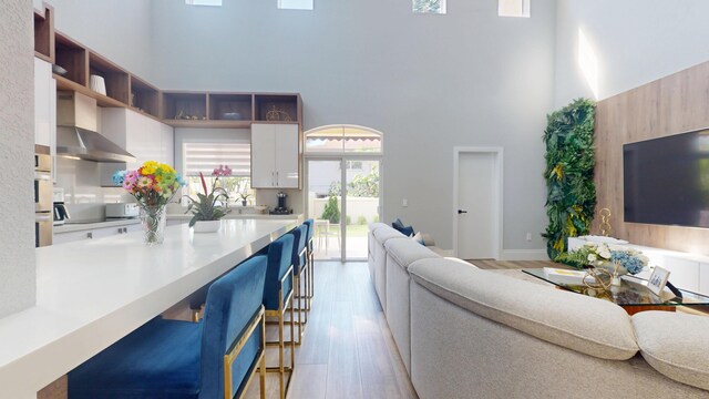 1942 NE 6th St, Deerfield Beach, FL 33441 - living area with baseboards, light wood-type flooring, and a towering ceiling