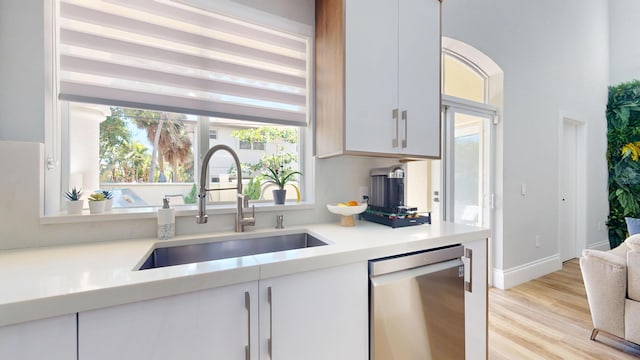 1942 NE 6th St, Deerfield Beach, FL 33441 - kitchen with light countertops, a sink, white cabinetry, dishwasher, and light wood-style flooring