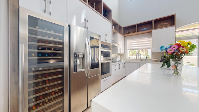 1942 NE 6th St, Deerfield Beach, FL 33441 - kitchen featuring light countertops, wine cooler, a sink, open shelves, and white cabinets