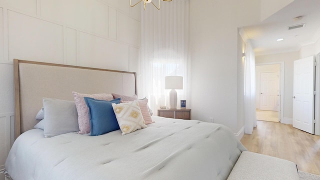 1942 NE 6th St, Deerfield Beach, FL 33441 - bedroom featuring a chandelier, a decorative wall, baseboards, visible vents, and light wood-style floors