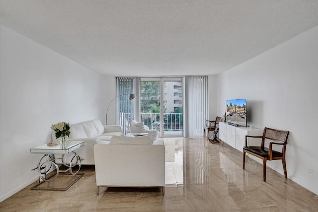 living area with baseboards, marble finish floor, a textured ceiling, and a wall of windows