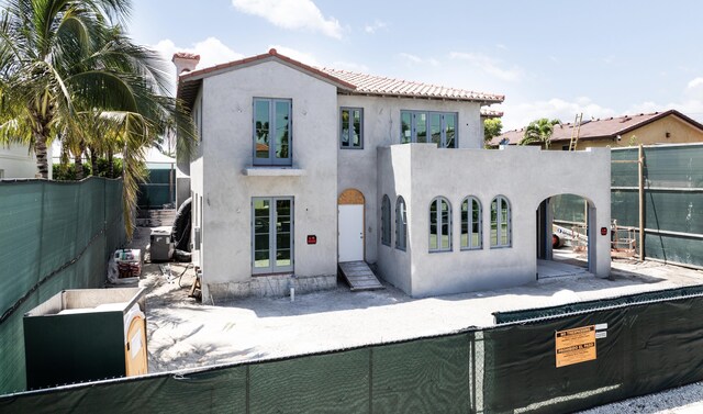 view of front of house with a tile roof, french doors, a fenced backyard, and stucco siding