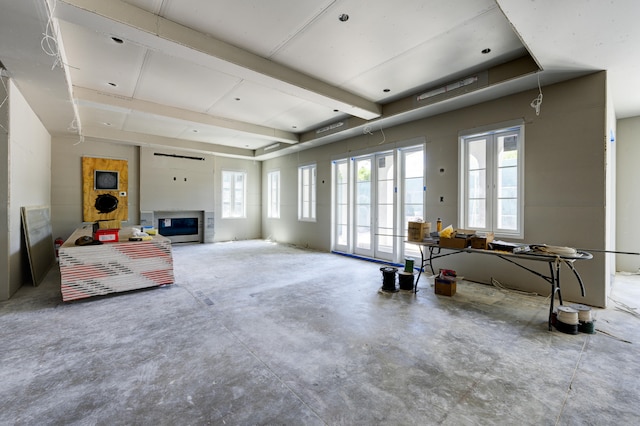 interior space featuring a glass covered fireplace and unfinished concrete flooring
