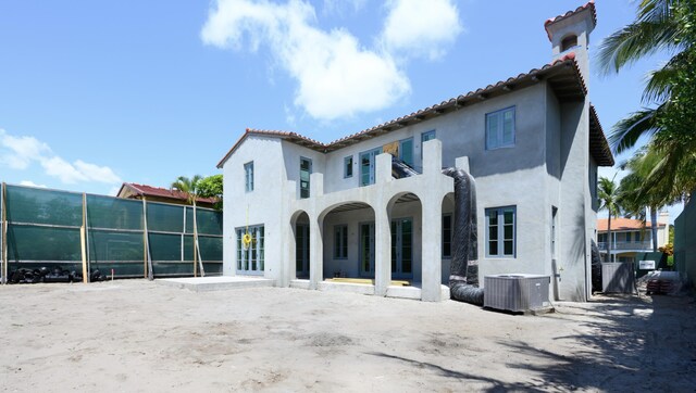 back of house with central air condition unit, a tile roof, and stucco siding
